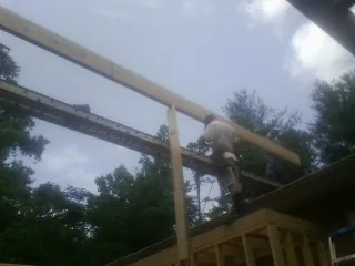 Carpenter setting a ridge beam over a new addition frame — Ice Dam Removal by Roofing Brothers in Helper