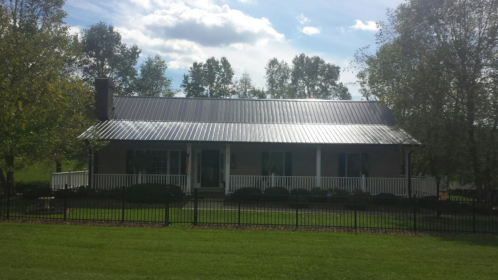 Gray metal roof on a brick ranch with a full width front porch — Gutter Guard Installation work by our crew in Helper