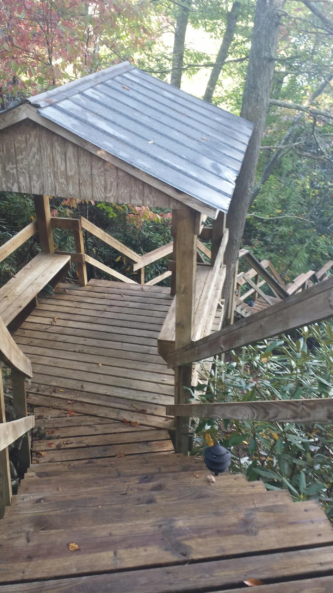 Metal roofed shelter over wooden steps on a wooded walkway — Skylight Repair & Installation work by our crew in Helper