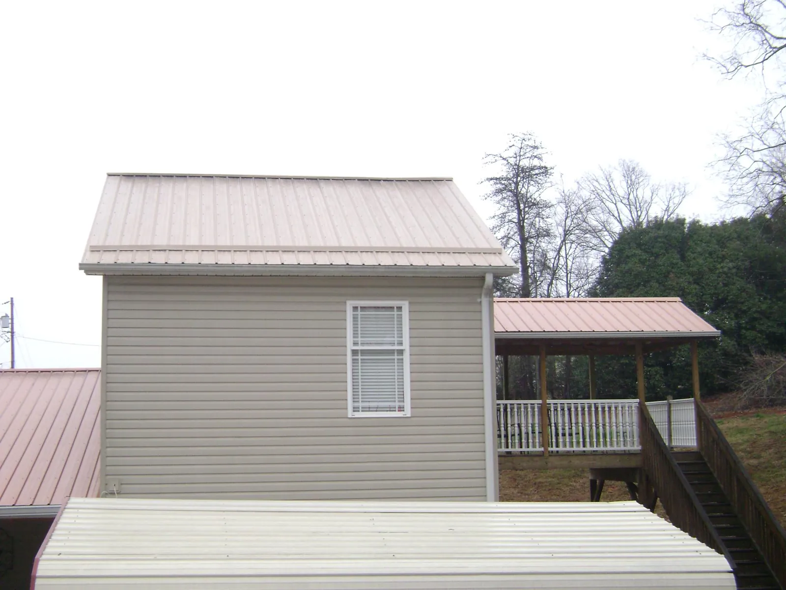 Tan metal roofs on a two story addition and attached porch, from a Roof Replacement job in Helper
